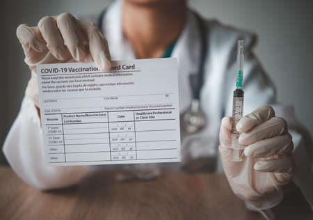 Coronavirus vaccination record card in the hands of a doctor to a patient who has already been vaccinated with Coronavirus. .Coronavirus preventionの写真素材