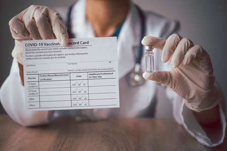 Coronavirus vaccination record card in the hands of a doctor to a patient who has already been vaccinated with Coronavirus. .Coronavirus preventionの写真素材