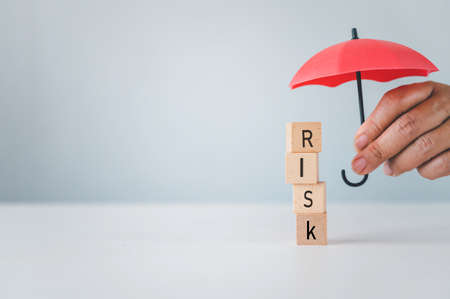 Hand hold umbrella protection wooden block with the word "RISK". Concept prevent riskの写真素材