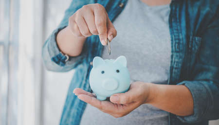 Hand holding coin with pig piggy bank. Saving and financial accounts conceptの写真素材