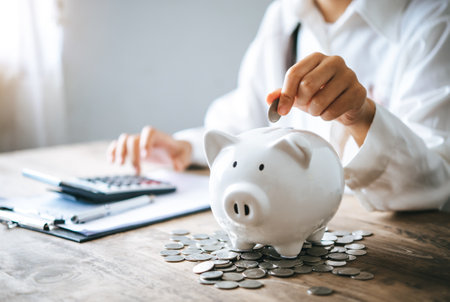 Hand holding coin with pig piggy bank. Saving and financial accounts conceptの写真素材
