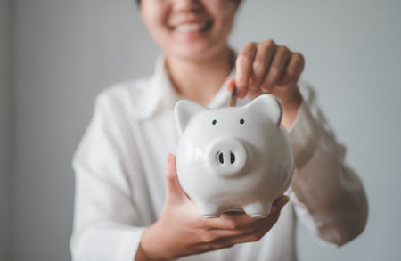 Hand holding coin with pig piggy bank. Saving and financial accounts conceptの写真素材