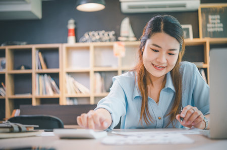 Business asian woman sitting at a desk at an office By using the calculator to work. Business Concept Analysis and Planningの写真素材