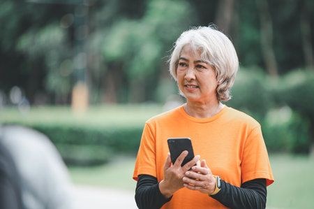 Elderly, white-haired Asian woman exercising in the park early in the morning.の写真素材