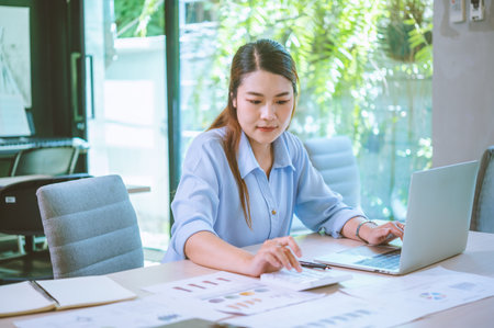Business asian woman sitting at a desk at an office By using the calculator to work. Business Concept Analysis and Planningの写真素材