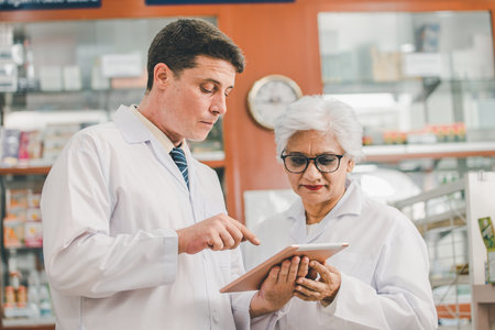skilled pharmacist is consulting, analyzing the use of drugs to recommend and supervise patients according to prescriptions in modern pharmacies.の写真素材