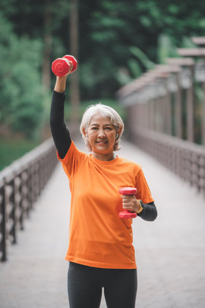 Elderly, white-haired Asian woman exercising in the park early in the morning.の写真素材
