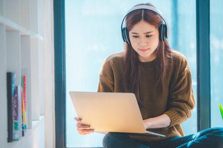 young student wearing headphones studies online, distance learning, and keeps up to date on the...