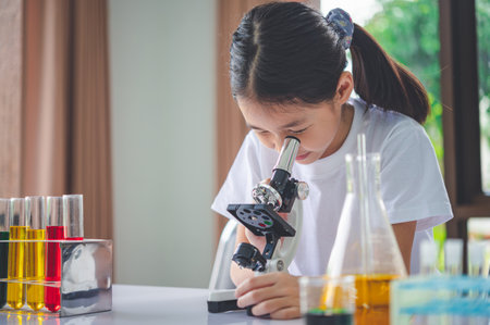 little scientist looking through a microscope and test tubes filled with chemicals for learning about science and experiments.の写真素材