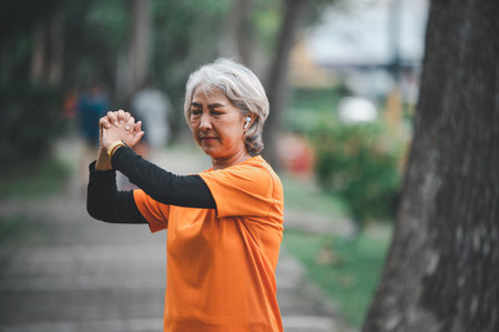 Elderly, white-haired Asian woman exercising in the park early in the morning.の写真素材