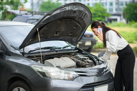 female motorist is calling an insurance or recovery service officer for assistance related to a car...