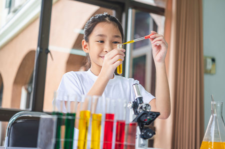 little scientist looking through a microscope and test tubes filled with chemicals for learning about science and experiments.の写真素材