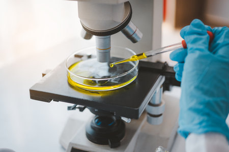 Female researchers are experimenting with pipette dropping a sample into a test tube in an...
