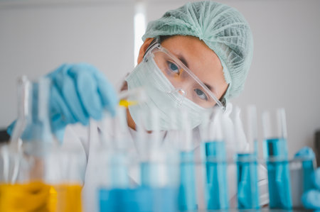 Female researchers are experimenting with pipette dropping a sample into a test tube in an...