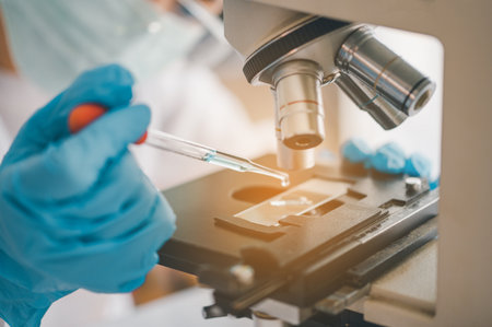 Female researchers are experimenting with pipette dropping a sample into a test tube in an...