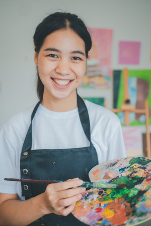 Portrait of Art student smiling happily while with watercolor painting on canvas doing some art projects on studio workshopの写真素材
