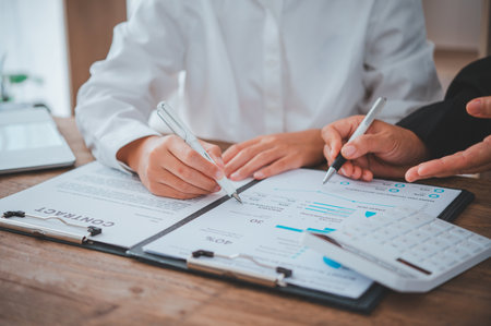 Business team working with laptop and calculator in open space office. Meeting report in progressの写真素材