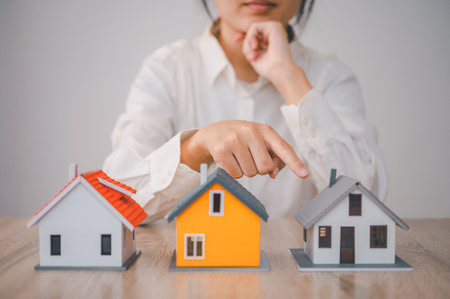 woman with a house model in front of her is making a decision to buy a new home. concept of buying a houseの写真素材