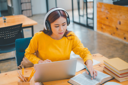 young student wearing headphones studies online, distance learning, and keeps up to date on the global coronavirus pandemic.の写真素材