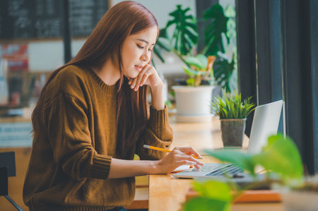 young student wearing headphones studies online, distance learning, and keeps up to date on the global coronavirus pandemic.の写真素材