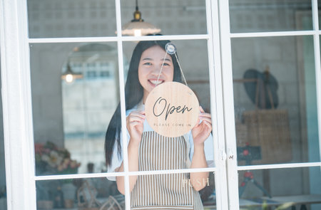 Smiling online small business owner holding a sign saying "Open" and happily working at a courier business offering orders and products to customers.Online retailer - online shopping.の写真素材