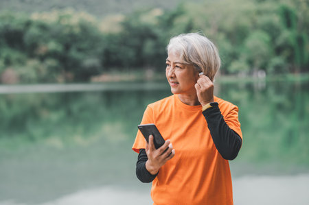 Elderly, white-haired Asian woman exercising in the park early in the morning.の写真素材