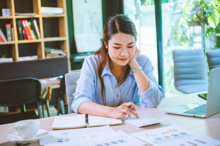 Business asian woman sitting at a desk at an office By using the calculator to work. Business Concept Analysis and Planningの写真素材