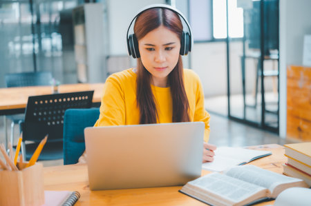 young student wearing headphones studies online, distance learning, and keeps up to date on the global coronavirus pandemic.の写真素材