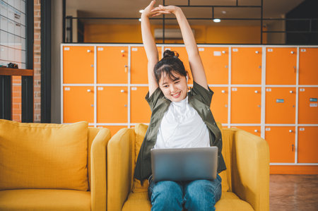 Young Asian freelancers are stretching and relaxing after working on a laptop.の写真素材