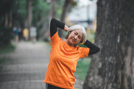 Elderly, white-haired Asian woman exercising in the park early in the morning.の写真素材
