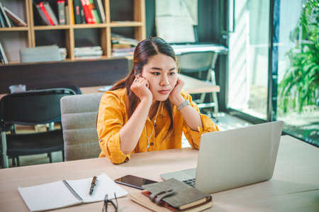Tired and bored businesswoman working online on her laptop in a cafeの写真素材
