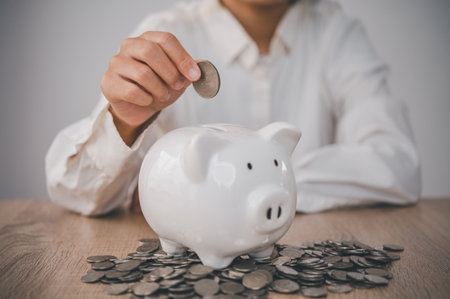Hand holding coin with pig piggy bank. Saving and financial accounts conceptの写真素材