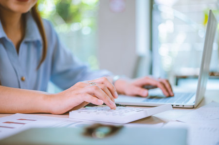 Business asian woman sitting at a desk at an office By using the calculator to work. Business Concept Analysis and Planningの写真素材