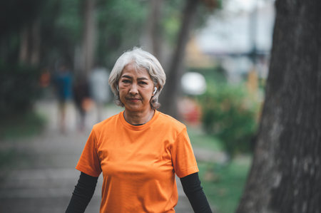 Elderly, white-haired Asian woman exercising in the park early in the morning.の写真素材