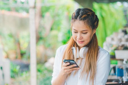 Smiling young woman using mobile phone checking social media, playing game, shopping online, ordering delivery relaxの写真素材