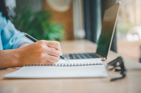 Asian teenage students taking online distance learning on laptop, in cafeの写真素材
