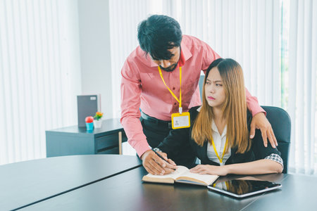 Boss or supervisor touching female employee's shoulder Causing young employees to resist because they are uncomfortable and afraid of being sexually abused. Concept of sexual harassment in the workplaceの写真素材