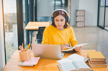 young student wearing headphones studies online, distance learning, and keeps up to date on the global coronavirus pandemic.の写真素材