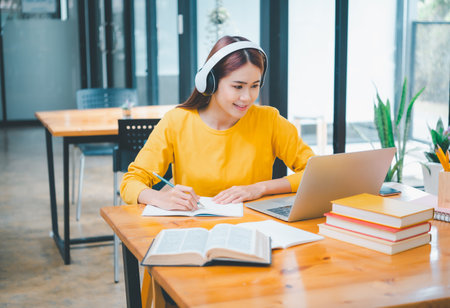 young student wearing headphones studies online, distance learning, and keeps up to date on the global coronavirus pandemic.の写真素材