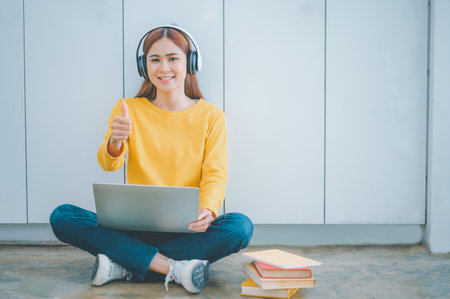 young student wearing headphones studies online, distance learning, and keeps up to date on the global coronavirus pandemic.の写真素材