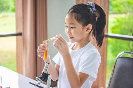 little scientist looking through a microscope and test tubes filled with chemicals for learning about science and experiments.の写真素材