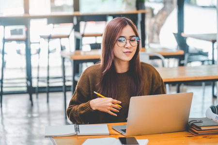 young student wearing headphones studies online, distance learning, and keeps up to date on the global coronavirus pandemic.の写真素材