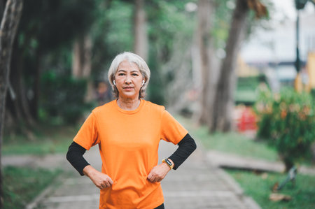 Elderly, white-haired Asian woman exercising in the park early in the morning.の写真素材