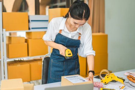 online small business owner scans a barcode-labeled parcel with a barcode scanner to verify a...
