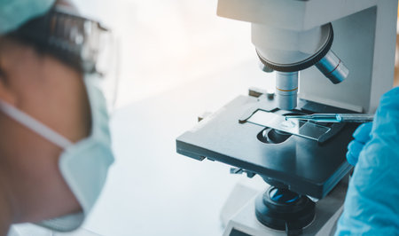 Female researchers are experimenting with pipette dropping a sample into a test tube in an...
