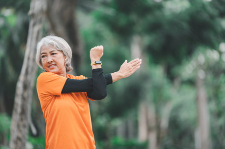 Elderly, white-haired Asian woman exercising in the park early in the morning.の写真素材