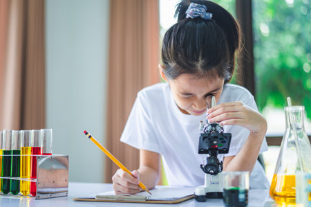 little scientist looking through a microscope and test tubes filled with chemicals for learning about science and experiments.の写真素材
