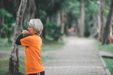 Elderly, white-haired Asian woman exercising in the park early in the morning.の写真素材