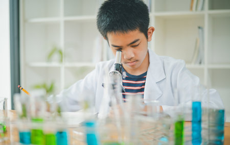Asian male science students looking through a microscope and tests of plants in the classroom....