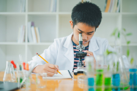 Asian male science students looking through a microscope and tests of plants in the classroom....